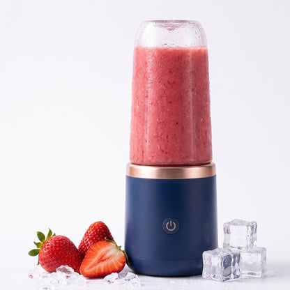 Navy portable blender with a red smoothie, next to strawberries and ice cubes