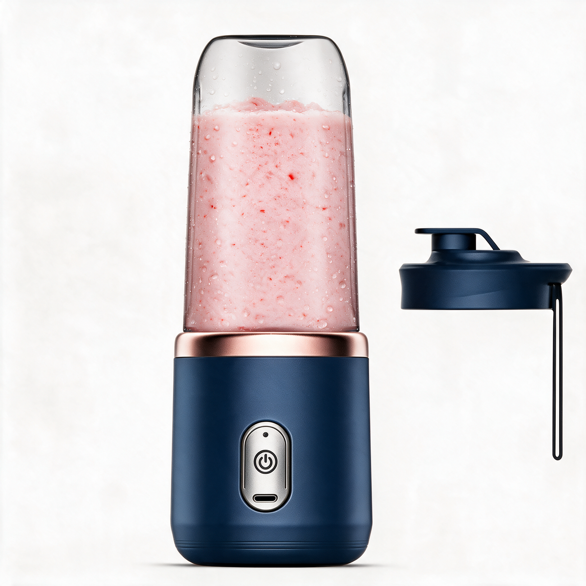 Navy portable blender with its travel lid and carrying strap beside it